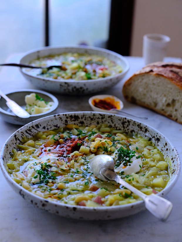 Bowls of soup on a marble table near a window