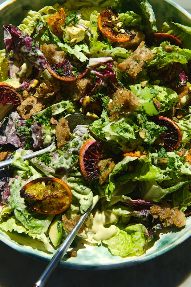 Caesar salad in a large bowl with salad tongs