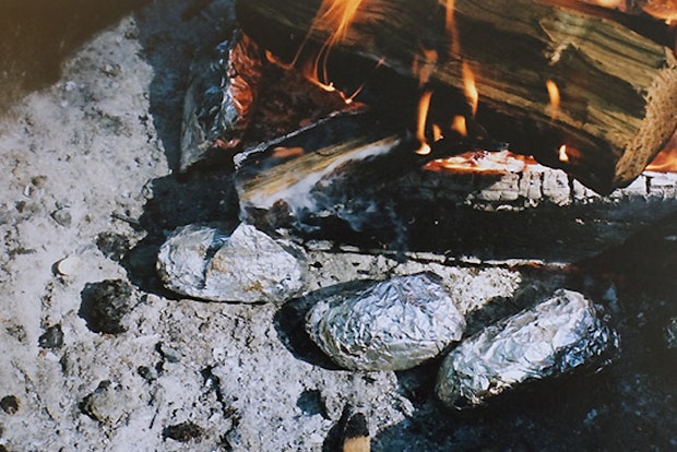 In Folie gewickelte Ofenkartoffeln auf dem Feuer