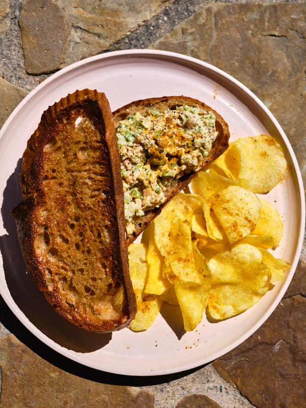 Sandwich mit Kichererbsensalat auf einem Teller mit Kartoffelchips