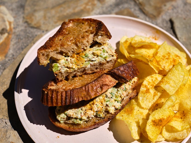 Close-up Photo of Chickpea Salad Sandwich on a Plate cut in Half on a Plate with Potato Chips