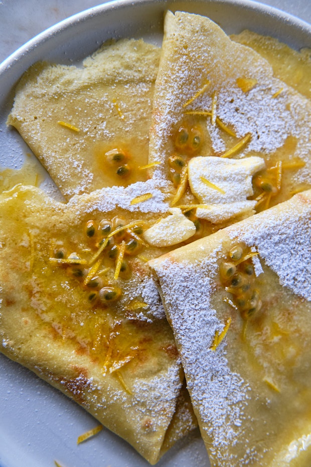 crepes serves on a white plate with butter and dusted with powdered sugar