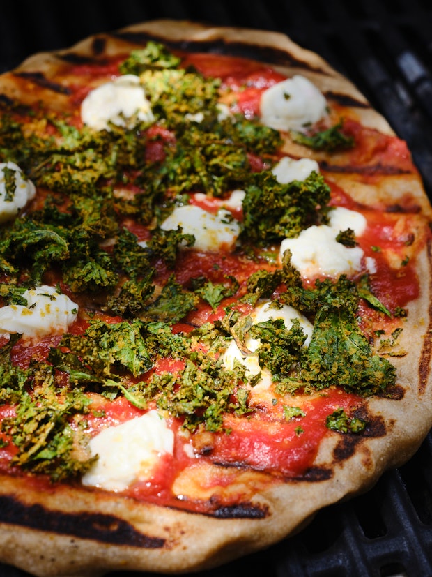 Grilled Pizza topped with Kale, Tomato Sauce and Mozzarella” border=