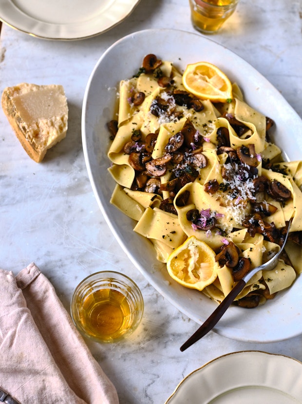 Homemade Pappardelle on a plate with sliced ​​mushrooms and lemon