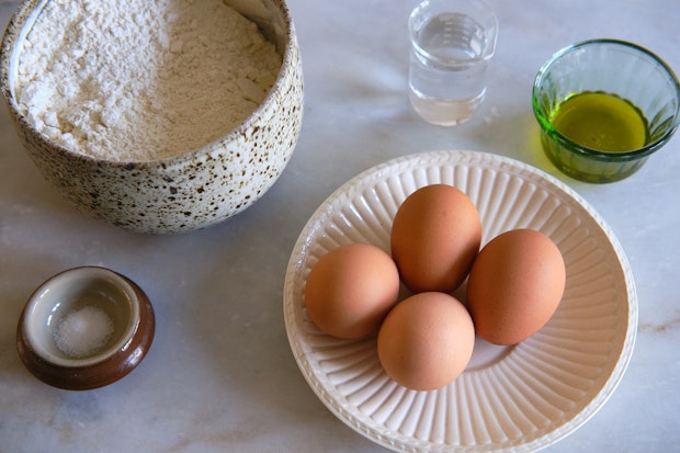 ingredients for making fresh tagliatelle pasta including flour, eggs, salt, and olive oil