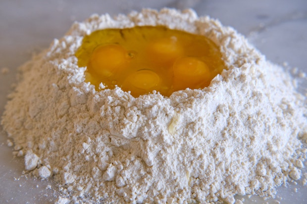 a mound of flour filled with eggs for pasta dough