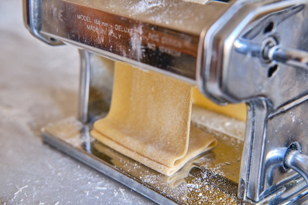 pasta machine rolling out a sheet of tagliatelle dough