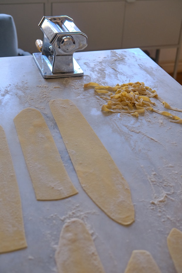 pasta machine and fresh pasta sheets on a marble counter