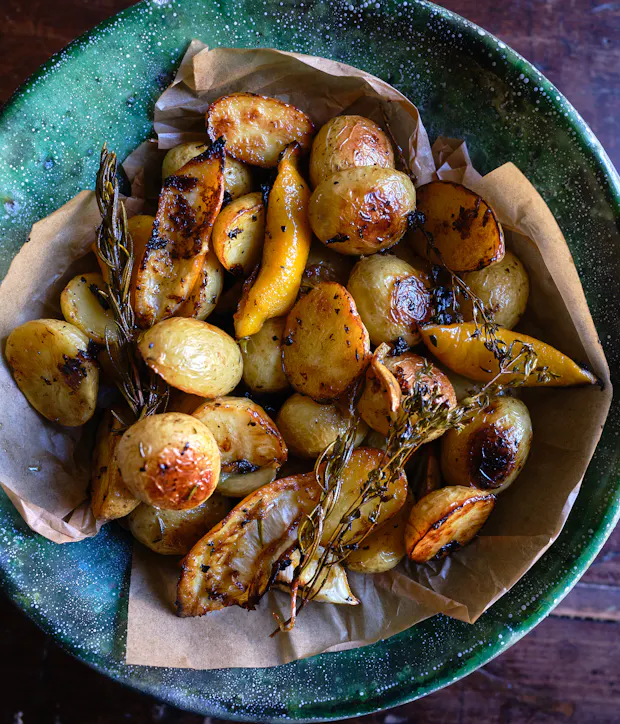 roasted potatoes in a bowl with garlic and herbs and lemon
