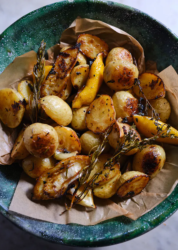 roasted potatoes in a bowl with garlic and herbs and lemon
