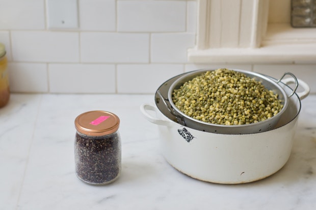 mung beans draining above a large cast iron pot and a jar of quinoa to the side