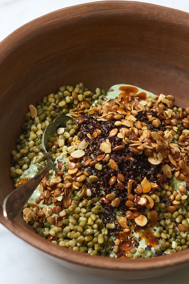 Big bowl filled with mung beans, quinoa, yogurt dressing and paprika oil
