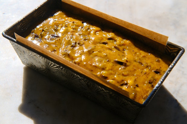 Unbaked pumpkin bread batter in a parchment lined bread tin before baking
