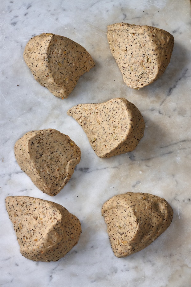 seeded flabread dough divided on a marble counter