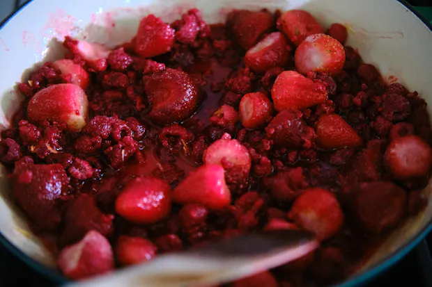 Strawberries and raspberries in a pot starting to simmer for jam