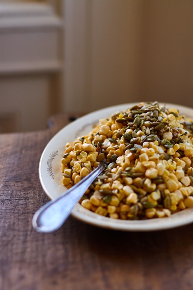 Ensalada de maíz de verano en un plato con una cuchara para servir