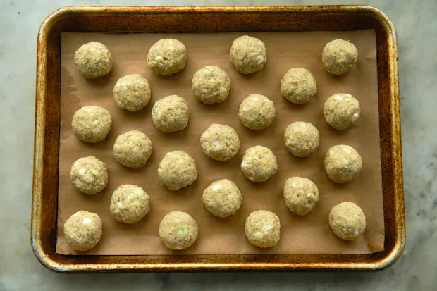Tempeh ponzu balls arranged on a parchment-lined baking sheet prior to cooking