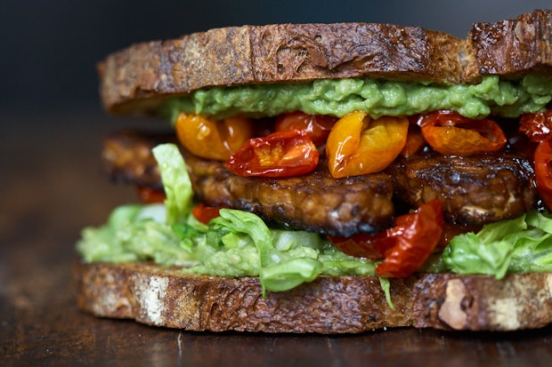 TLT sandwich pictured from the side with lettuce and roasted cherry tomatoes