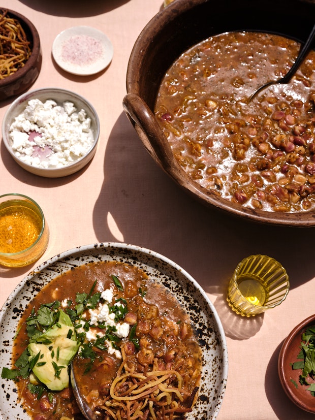 A Cazuela of Pozole on a Table with a Range of Toppings