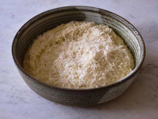 Part-baked dip sprinkled with grated cheese