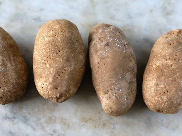 Baked potatoes prior to baking with holes poked into skin by a fork