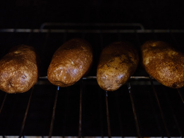 Potatoes baking in a row on and oven rack in an oven
