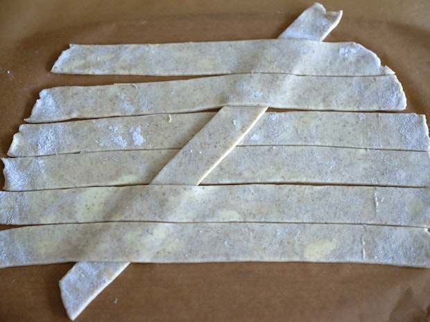 pie crust dough strips being woven into a lattice pie crust