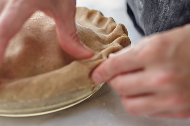 crimping the edges of a berry pie crust with thumb and fingers