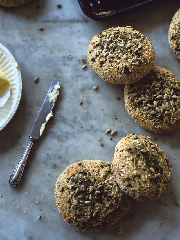 Small round homemade breads topped with seeds on a marble counter