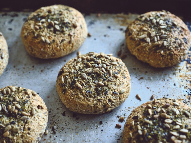 Small round homemade breads topped with seeds on a marble counter