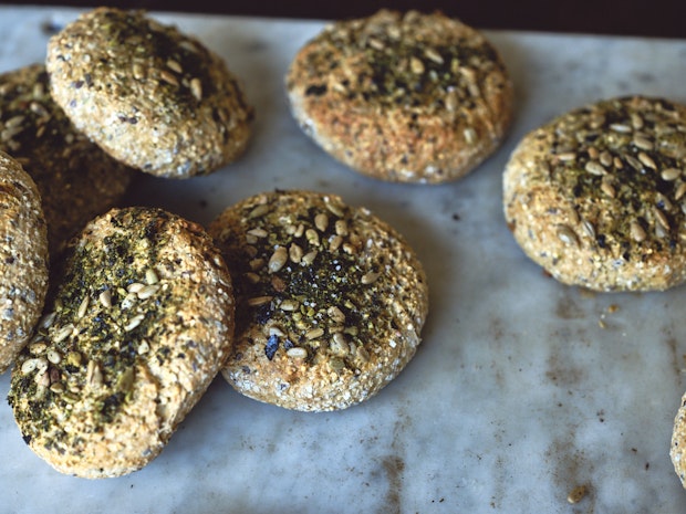 Small round homemade breads topped with seeds on a marble counter