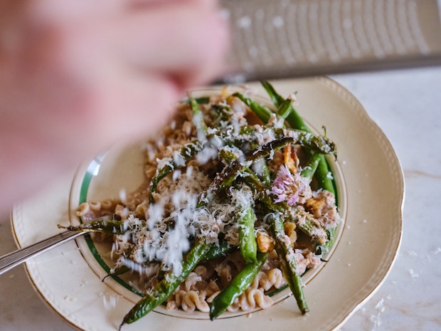 Grate parmesan cheese over a bowl of green beans in blister form