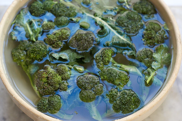 washing broccoli in large bowl of water