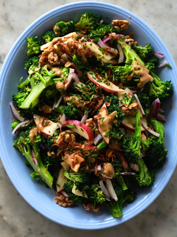 broccoli apple salad drizzled with dressing on a blue plate