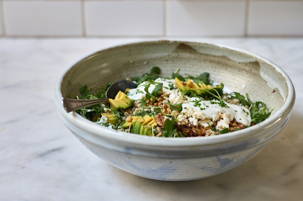 big salad bowl filled with barley, cheese, avocado, walnuts and a yogurt dressing