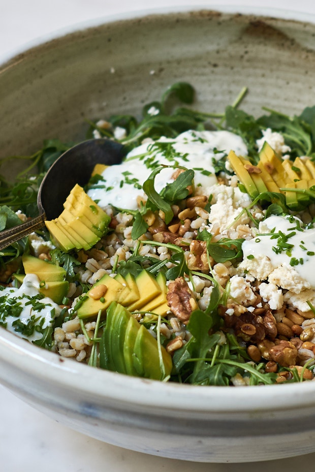 big salad bowl filled with barley, cheese, avocado, walnuts and a yogurt dressing