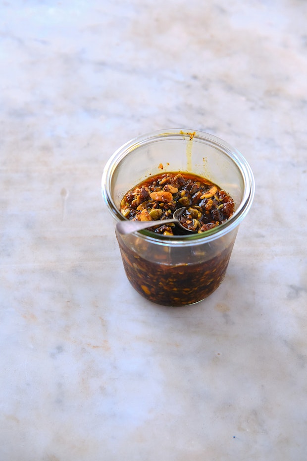 Chili crisp in a glass jar on a marble counter