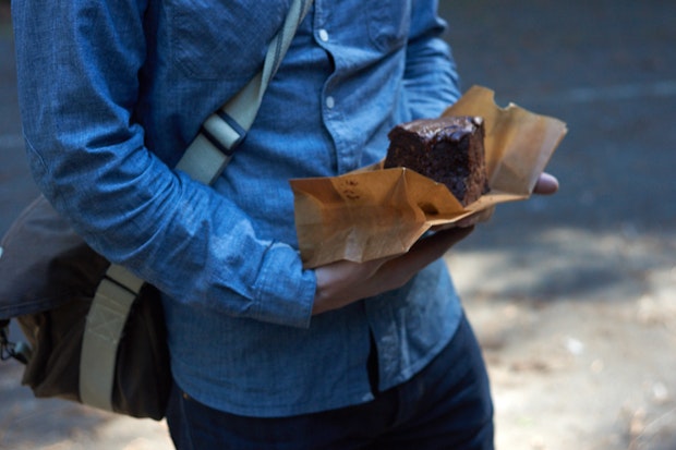 a large slice of chocolate bundt cake being held on a piece of parchment paper