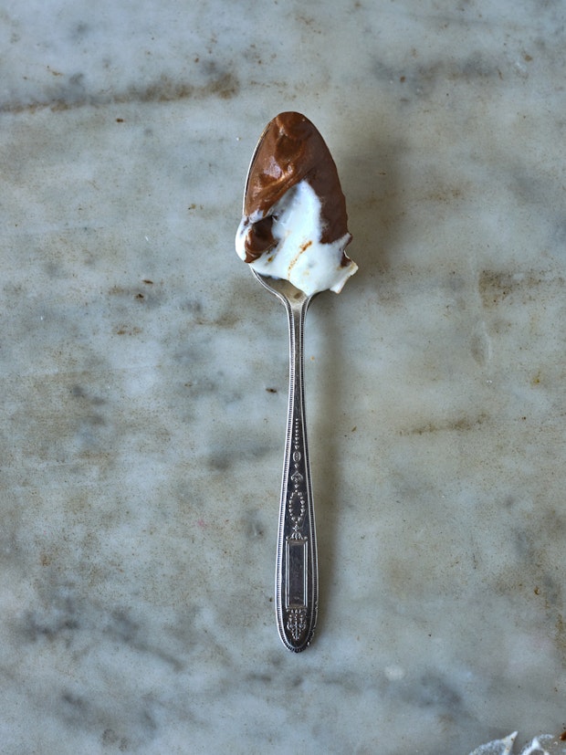 a bite of chocolate pudding on a spoon with a bit of whipped cream