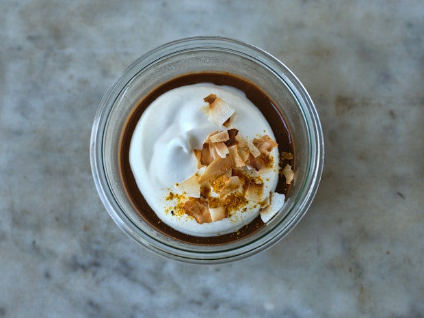 chocolate pudding in a glass bowl with whipped cream and toasted coconut on top