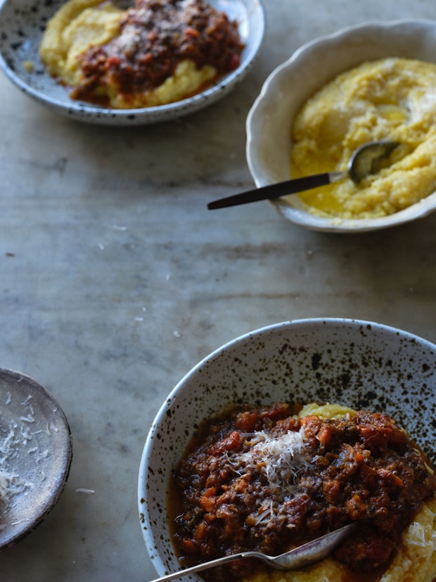 table with bowls of polenta being served topped with mushroom ragu