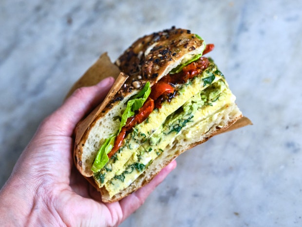 a hand holding a frittata sandwich