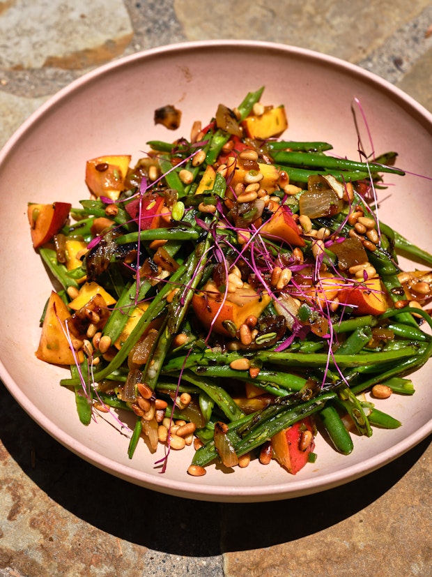 green bean salad with peaches, nuts, caramelized onions in a pink bowl
