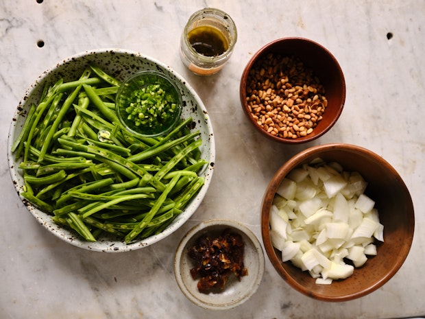 ingredients for green bean salad arranged in small bowls