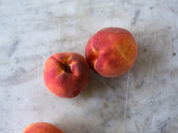 two peaches on a marble counter