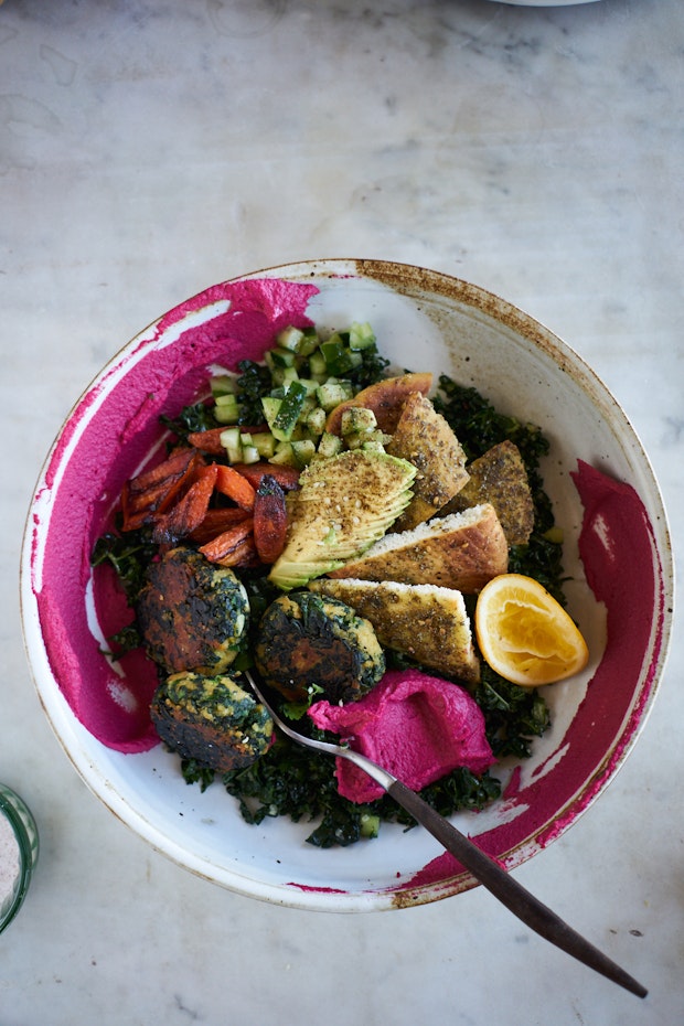 Spinach flecked falafel in a bowl with sides.