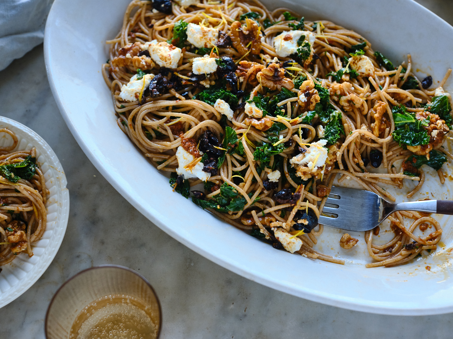 spaghetti tossed with harissa oil, kale, black olives and walnuts served on a platter