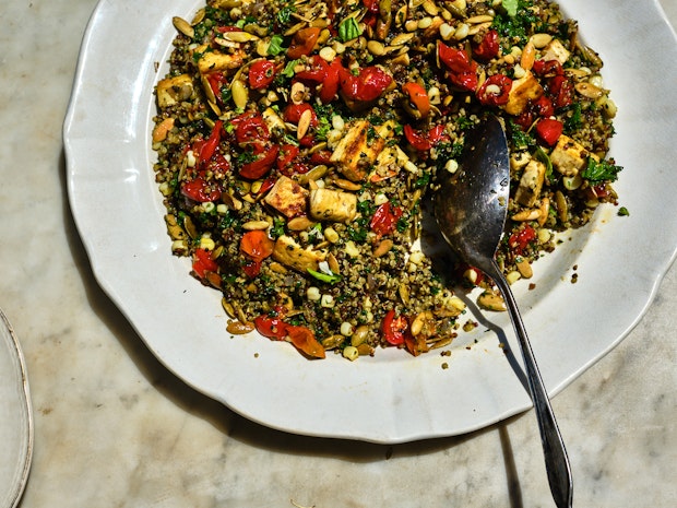 plate of quinoa mixed with roasted tomatoes, tofu, seeds, and kale