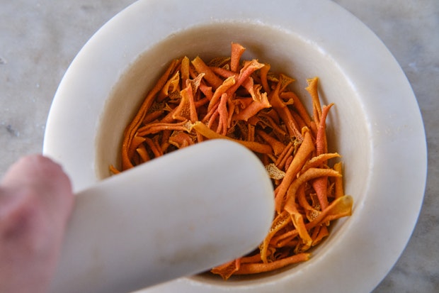 dried orange peel in mortar and pestle before being crushed into an orange peel powder