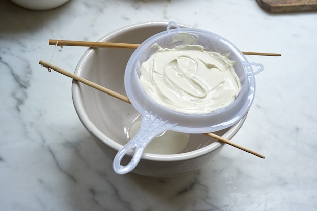 yogurt being strained into a bowl to make labneh